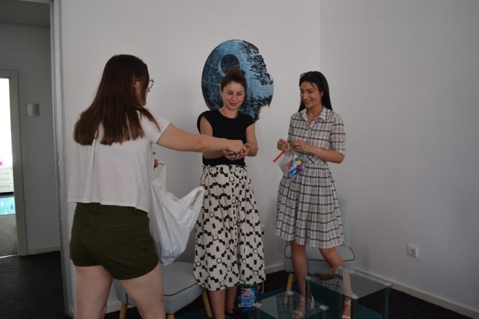 Three women are collecting caps into a bag.