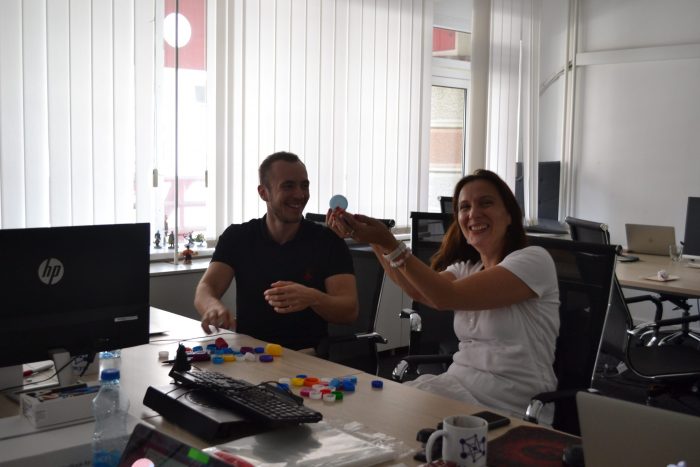 Two people are sitting at the table, sorting caps.