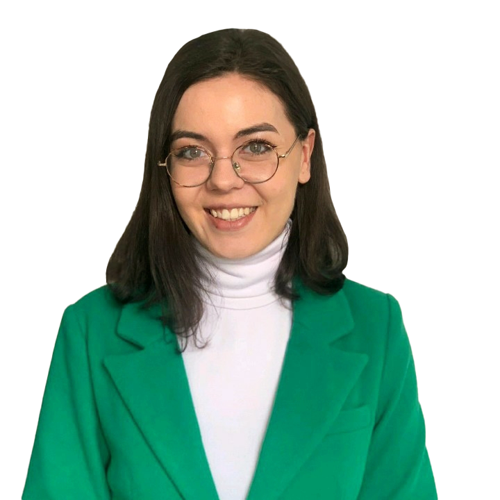 A smiling woman with glasses, wearing a green suit.